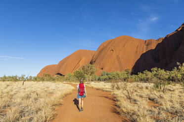 Australien, Northern Territory, Rückansicht einer Frau beim Wandern durch die Wüstenlandschaft des Uluru Kata Tjuta National Park - FOF12057