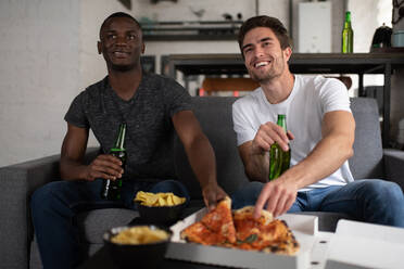 Fröhliche multiethnische Freunde essen Pizza und sehen sich ein Fußballspiel an - CAVF93337