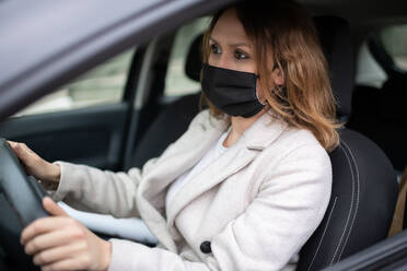 Frau mit Schutzmaske fährt Auto - CAVF93340