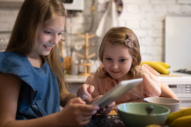 Mädchen spielt Spiel auf Tablet mit Schwester - CAVF93353