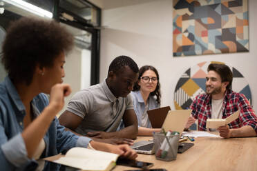 Black man using laptop amidst colleagues - CAVF93365