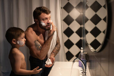 Father showing son how to smear shaving foam - CAVF93373