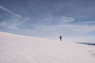 Junger Mann wandert bergauf auf Eis Schnee gegen blauen Himmel, Gredos, Spanien - CAVF93433