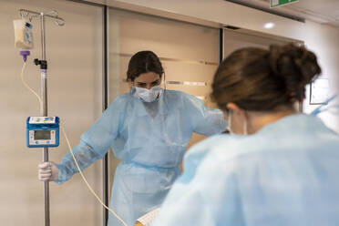 Zwei Krankenschwestern helfen einem Patienten beim Gehen auf dem Flur - CAVF93438