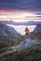 Photographer watching the sunrise over a sea of clouds - CAVF93440