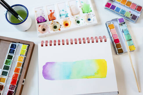 Abstract of rainbow water color painting with equipment on table - GEMF04662