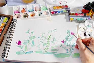 Frau malt botanische Pflanzen und Blumen auf Papier am Tisch - GEMF04663
