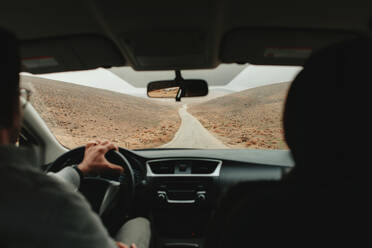 Rückenansicht eines reisenden männlichen Fahrers, der im Wadi Rum Sandsteintal während einer Autoreise in Jordanien fährt - ADSF20807