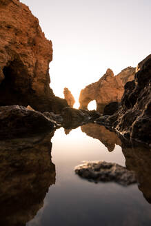 Ruhiges, sauberes Wasser in einer Bucht in der Nähe von rauen Klippen bei Sonnenuntergang in Ponta da Piedade an der Algarve, Portugal - ADSF20880