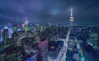 Luftaufnahme der Stadt New York mit leuchtenden Türmen und beleuchteten Straßen unter bewölktem Nachthimmel - ADSF20972