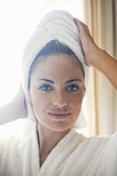 Smiling woman wearing bathrobe and towel round her hair at home - AJOF01039