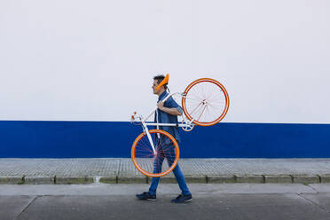Mann trägt Fahrrad, während er auf der Straße geht - XLGF01200