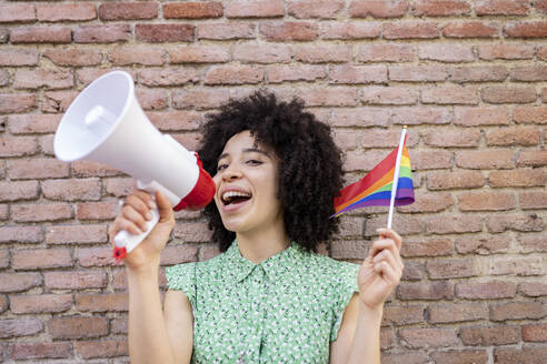 Mixed race woman protesting for LGBTQI rights against brick wall - JCCMF01237