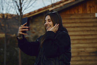 Glückliche junge Frau nimmt Selfie durch Handy durch Haus - ACPF01142