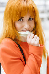 Smiling redhead woman holding turtleneck sweater - LJF02039