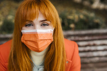 Redhead woman with gray eyes wearing protective face mask during COVID-19 - LJF02055