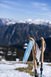Protective face mask hanging on ski pole against mountains - AKLF00059