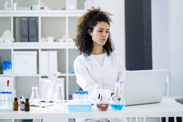 Ärztin bei der Arbeit am Laptop im Chemielabor - GIOF11233