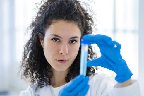 Young female scientist with test tube at chemistry lab - GIOF11250