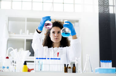 Wissenschaftlerin, die eine chemische Lösung in einem Becherglas im Labor überprüft - GIOF11256