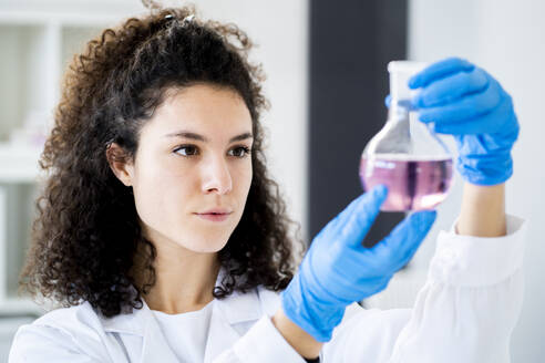 Young female doctor experimenting with chemical solution at clinic - GIOF11258