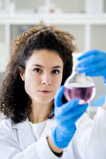 Female scientist with beaker at chemistry lab - GIOF11259