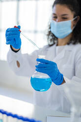 Female doctor analyzing solution in beaker at chemistry lab - GIOF11263