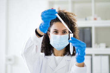 Junge Ärztin testet Lösung in einem Röhrchen im Chemielabor während einer Pandemie - GIOF11264