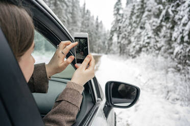 Woman photographing through mobile phone while sitting in car - VPIF03517