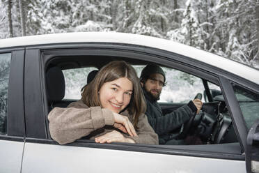 Lächelnde Frau schaut aus dem Fenster, während sie mit einem Mann im Auto sitzt - VPIF03519