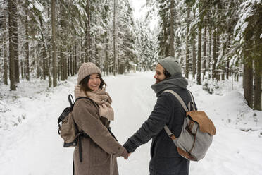 Junge Frau lächelt, während sie die Hand eines im Wald stehenden Mannes hält - VPIF03524