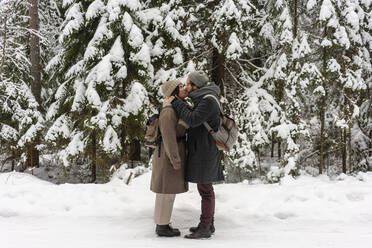 Junges Paar mit Rucksack, das sich küsst, während es im Wald steht - VPIF03527