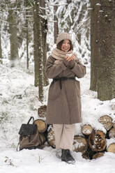 Frau mit Kaffeetasse, lächelnd im Wald stehend - VPIF03543