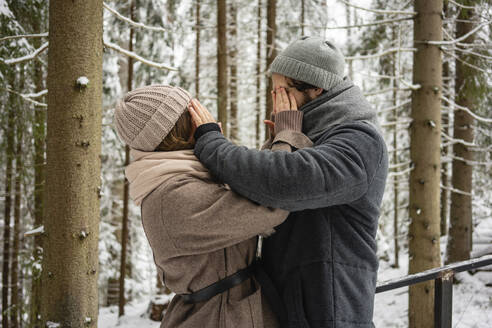 Junges Paar, das sich gegenseitig die Augen zuhält, während es im Wald steht - VPIF03550