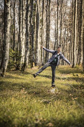 Hiker standing with arms outstretched on rock in forest - MSUF00517