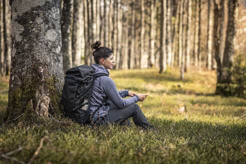 Rucksacktourist, der unter einem Baum im Wald sitzt und sich ausruht - MSUF00519