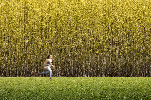 Mid adult woman running by tree farm - MSUF00523