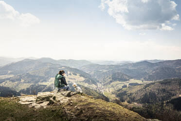 Female hiker looking at view while sitting on Kandel Mountain at Baden-Wurttemberg, Germany - MSUF00526