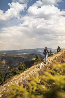 Mittlere erwachsene Frau beim Wandern mit Hund auf dem Kandel-Bergpfad in Baden-Württemberg, Deutschland - MSUF00527