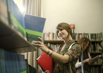 Junge Studentinnen wählen Bücher aus der Bibliothek aus - AJOF01051