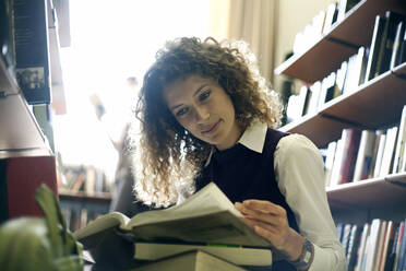 Junge Frau liest Bücher in der Bibliothek - AJOF01052