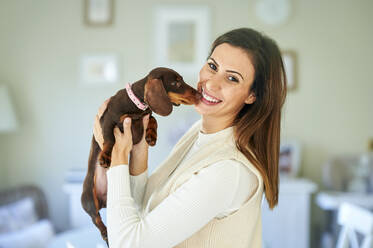 Lächelnde Frau mit Hund zu Hause - KIJF03611