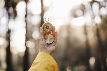Woman holding compass in forest - EBBF02476