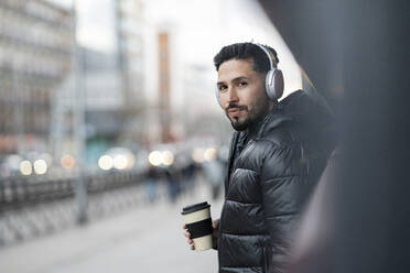 Handsome man with headphones holding coffee cup - JCCMF01256