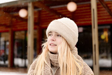 Thoughtful blond teenage girl looking away during winter - VYF00413