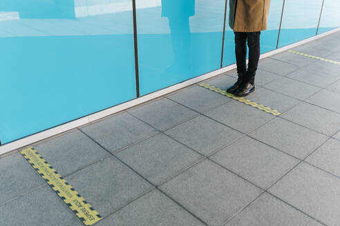 Man standing behind line of social distancing markings on footpath - EGAF01790