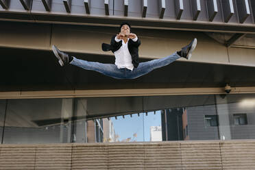 Male entrepreneur dancing while doing splits in mid-air - TCEF01564