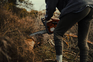 Jugendlicher schneidet Holz mit Kettensäge im Wald - ACPF01156