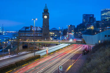 Germany, Hamburg, Vehicle light trails in front of Saint Pauli Piers clock tower at dawn - RJF00868