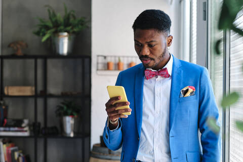 Mittlerer erwachsener Mann im Anzug, der ein Smartphone benutzt, lizenzfreies Stockfoto